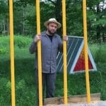 David Buckley Borden standing with one of his Harvard Forest art installations
