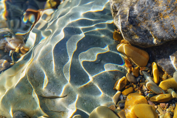view of multicolored rocks underwater with sunlight and water shadows
