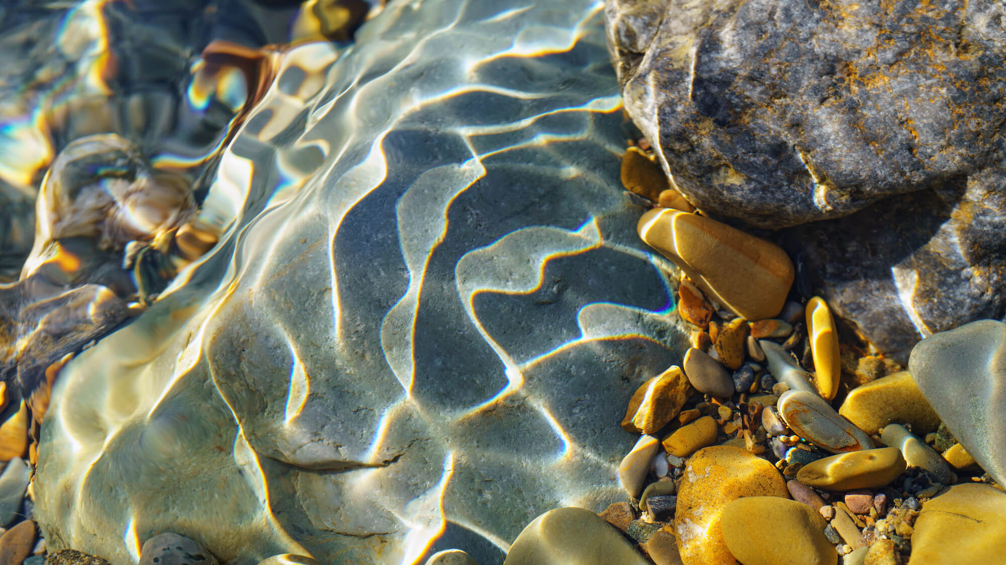 view of multicolored rocks underwater with sunlight and water shadows